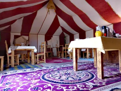 a room with a large tent with tables and chairs at Majestic Mirage Camp in Merzouga