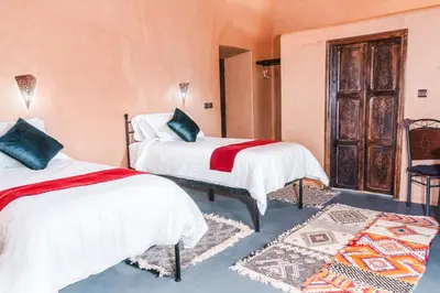 a bedroom with two beds and a door at Kasbah Tiziri in Kalaat MGouna