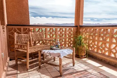 a porch with a bench and a table on a balcony at Kasbah Tiziri in Kalaat MGouna