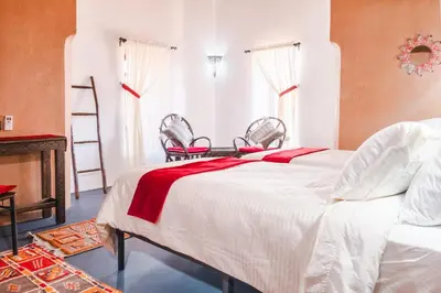 a bedroom with a bed with two chairs and a fireplace at Kasbah Tiziri in Kalaat MGouna