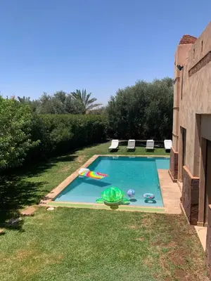 a swimming pool with chairs and a pool noodle in a yard at Sliwa house la Perle de la ville Ocre in Marrakech