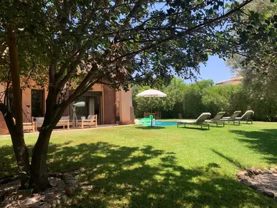 a yard with chairs and an umbrella and a pool at Sliwa house la Perle de la ville Ocre in Marrakech