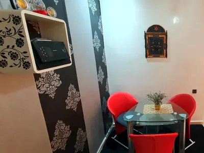 a small table and red chairs in a room at Hébergement sabrina in Fès