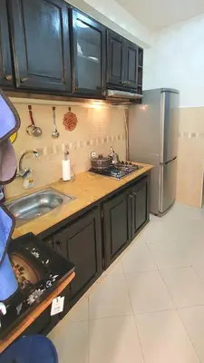 a kitchen with black cabinets and a stainless steel refrigerator at Hébergement sabrina in Fès