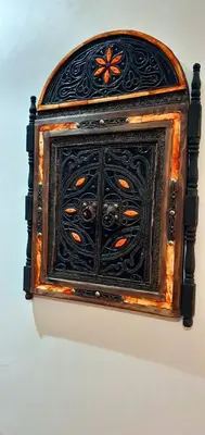 an old wooden cabinet with a black door on a wall at Hébergement sabrina in Fès