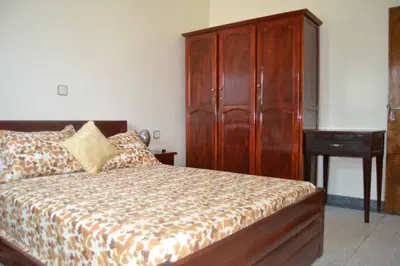 a bedroom with a bed and a wooden cabinet at Résidence Ayour in Ouarzazate