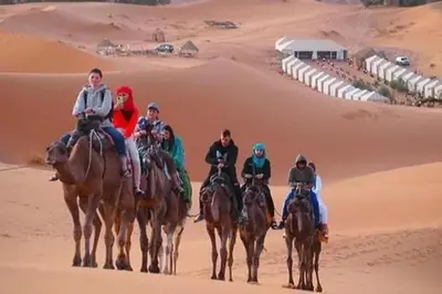 a group of people riding horses in the desert at Merzouga Camel Ride & Overnight Desert Camp in Merzouga