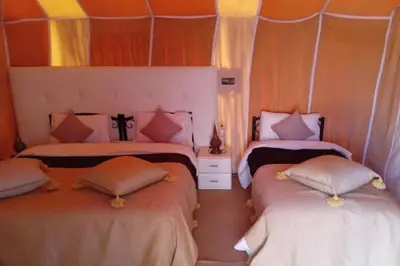 a bedroom with two beds with pillows at Merzouga Camel Ride & Overnight Desert Camp in Merzouga