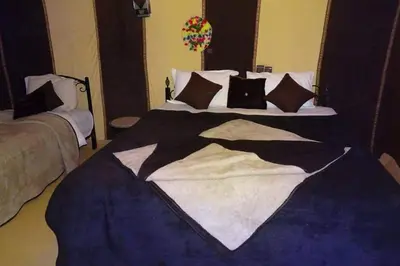 a large bed with a black and white comforter at Merzouga Camel Ride & Overnight Desert Camp in Merzouga