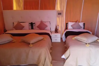 a bedroom with two beds with pillows at Merzouga Camel Ride & Overnight Desert Camp in Merzouga