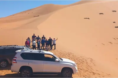 a group of people standing on top of a sand dune at Merzouga Camel Ride & Overnight Desert Camp in Merzouga