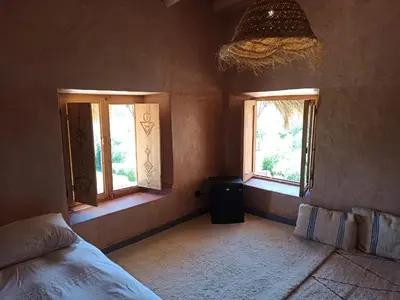 a bedroom with two windows and a bed in it at Trésors des Ancêtres in Ibrahene