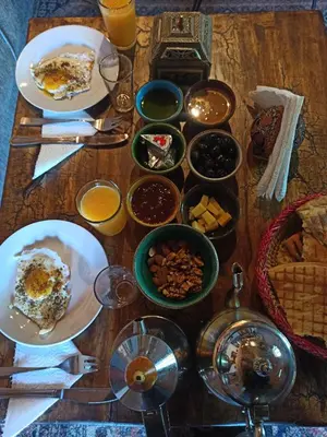 a wooden table topped with plates of food and drinks at Trésors des Ancêtres in Ibrahene