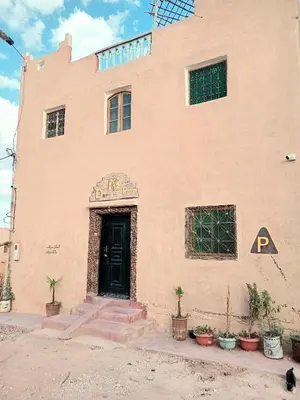 a building with a black door and some plants at Dar Mayssa Rose in Zawyat