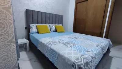 a bedroom with a bed with a blue comforter and yellow pillows at coin famille in Fès