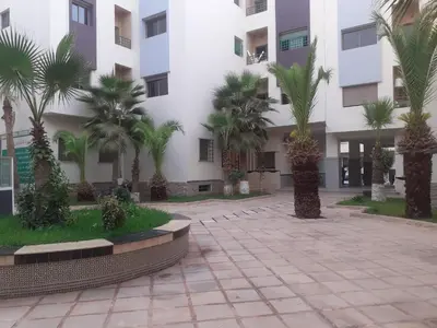 a courtyard in front of a building with palm trees at coin famille in Fès