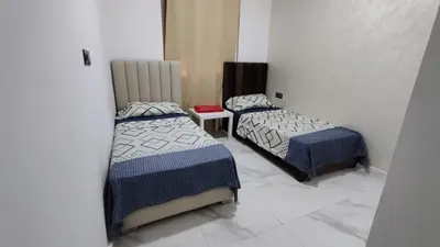 a bedroom with two beds and a table with a bedskirts at coin famille in Fès