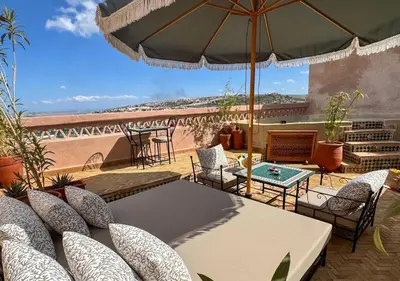 a patio with a table and chairs and an umbrella at Riad Dar Timrad in Fès