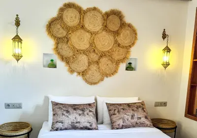 a bed with two pillows and a large orb on the wall at Riad Dar Timrad in Fès