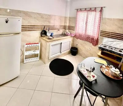 a small kitchen with a table and a refrigerator at A modern apartment in Fès