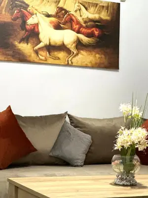 a couch with a painting of horses on the wall at A modern apartment in Fès