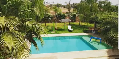 a large blue swimming pool in a yard with palm trees at Maison d'Hôtes à Marrakech in Marrakech