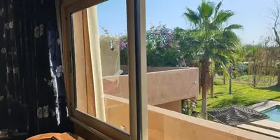 a window with a view of a pool and a palm tree at Maison d'Hôtes à Marrakech in Marrakech