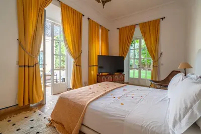 a bedroom with a large bed with yellow curtains at Villa Izza in Marrakech