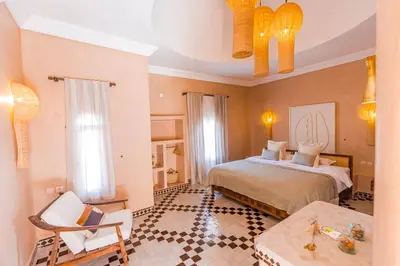 a bedroom with a bed and a chair in a room at Riad Villa Amood in Merzouga