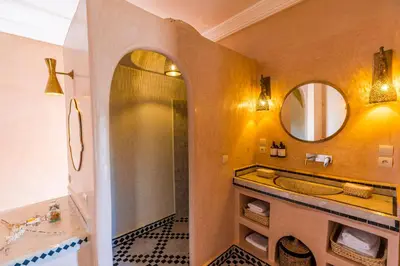 a bathroom with a tub and a sink and a mirror at Riad Villa Amood in Merzouga