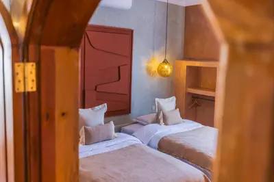 a bedroom with two beds and a mirror at Riad Villa Amood in Merzouga