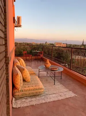 a patio with a couch and a table on a balcony at L'Oasis Villa in Marrakech