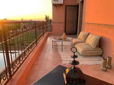 a balcony with a couch and a table at L'Oasis Villa in Marrakech