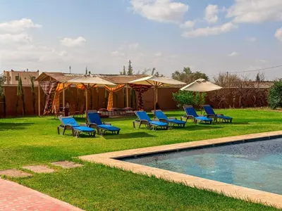 a yard with chairs and a pool and umbrellas at L'Oasis Villa in Marrakech
