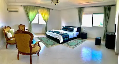 a bedroom with a bed and chairs and windows at L'Oasis Villa in Marrakech