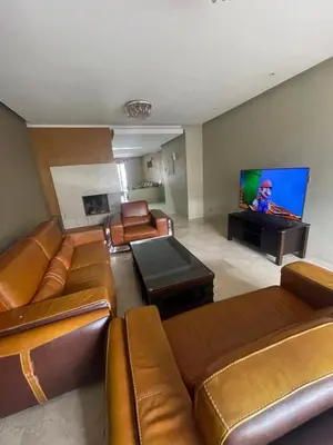 a living room with leather furniture and a flat screen tv at Prestigia luxury home in Fès