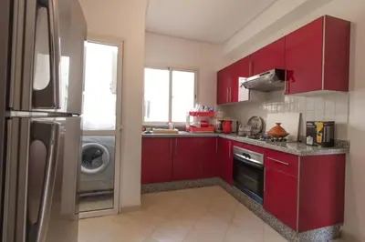 a kitchen with red cabinets and a stainless steel refrigerator at luxury Apartment Near Stadium and Airport in Fès