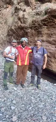 a group of three men standing on a rocky beach at Dar Laayoune in Kalaat MGouna