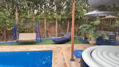 a swimming pool with a swing and an umbrella at La kasbah bleue in Marrakech