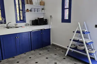 a kitchen with blue cabinets and a shelf with plates at La kasbah bleue in Marrakech