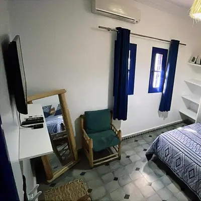 a bedroom with a chair and a bed and a television at La kasbah bleue in Marrakech