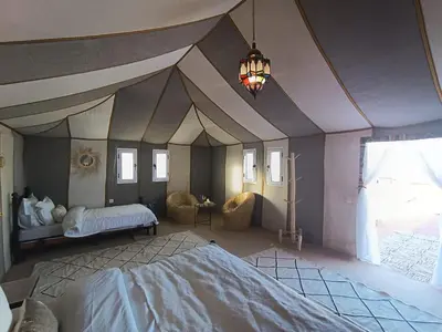 a bedroom with a large bed and a chandelier at Luxury Nomadic Tented Camp in Merzouga