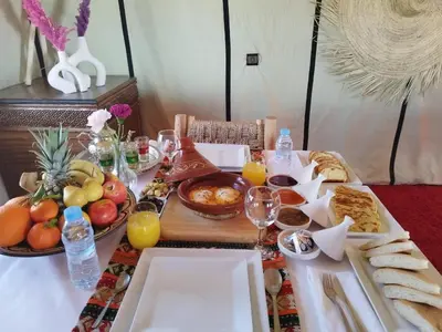 a table with breakfast foods and drinks on it at Luxury Nomadic Tented Camp in Merzouga