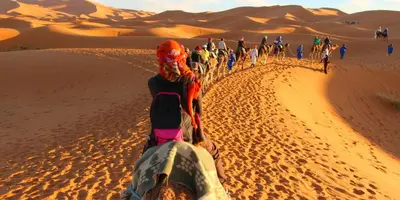 a group of people riding horses in the desert at Luxury Nomadic Tented Camp in Merzouga
