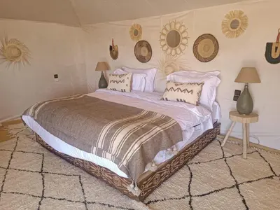 a bedroom with a large bed with two lamps and mirrors at Luxury Nomadic Tented Camp in Merzouga