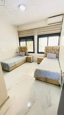 two beds in a room with white floors and windows at welcome to fez in Fès