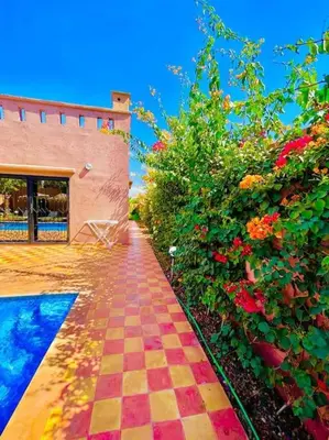 a tiled walkway in front of a building with flowers at Villa1 des tortues Marrakech in Aït Zat