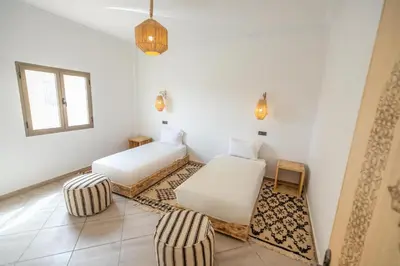 a white room with two beds and a chair at Dar Diafa in Merzouga