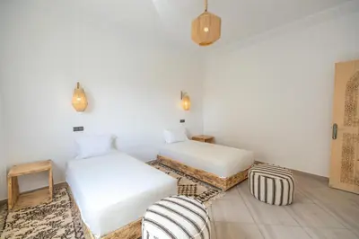 a room with two beds and a chair in it at Dar Diafa in Merzouga