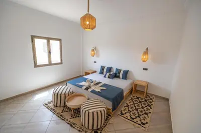 a bedroom with a bed and two chairs in it at Dar Diafa in Merzouga